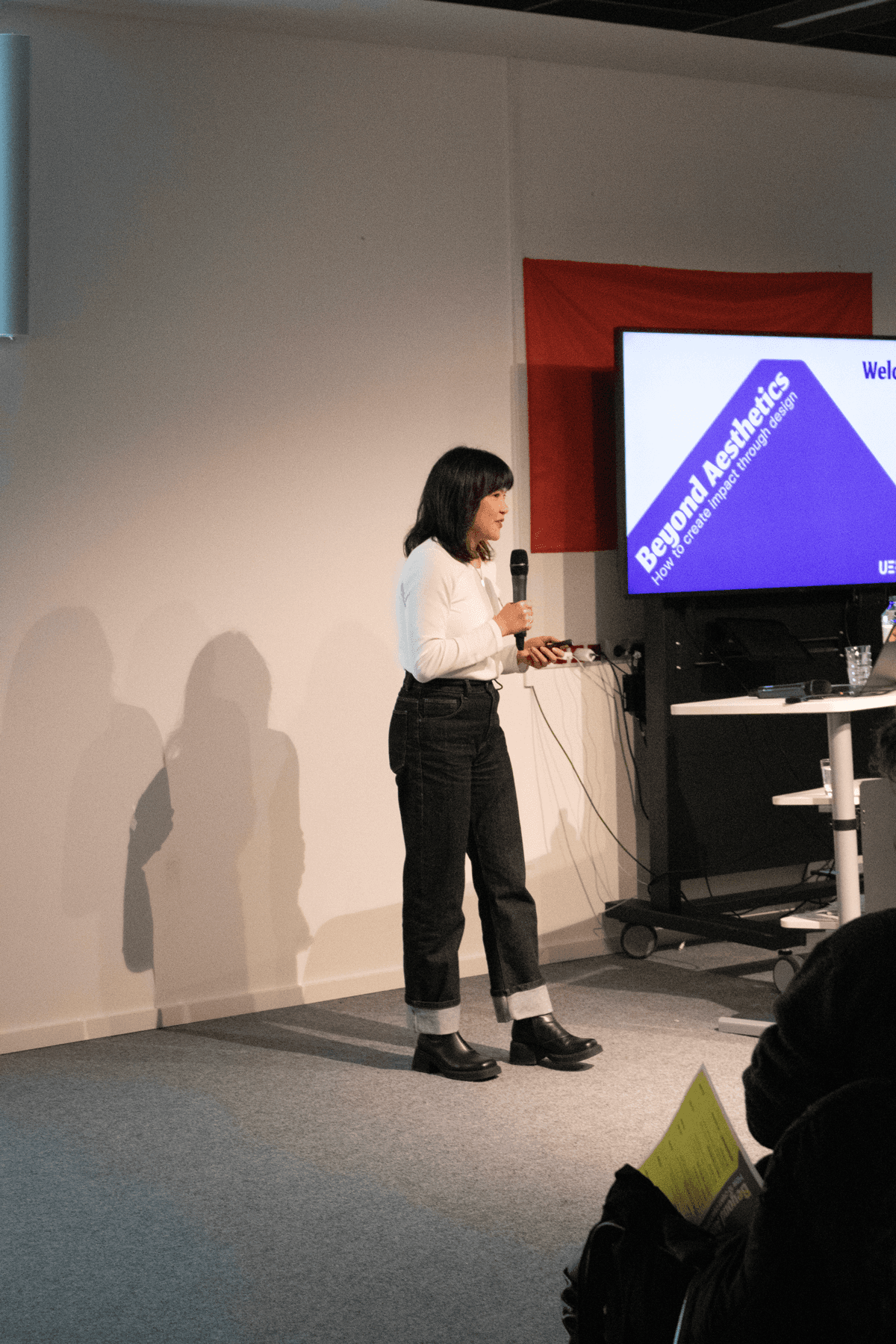 A speaker presenting next to a screen with the conference design