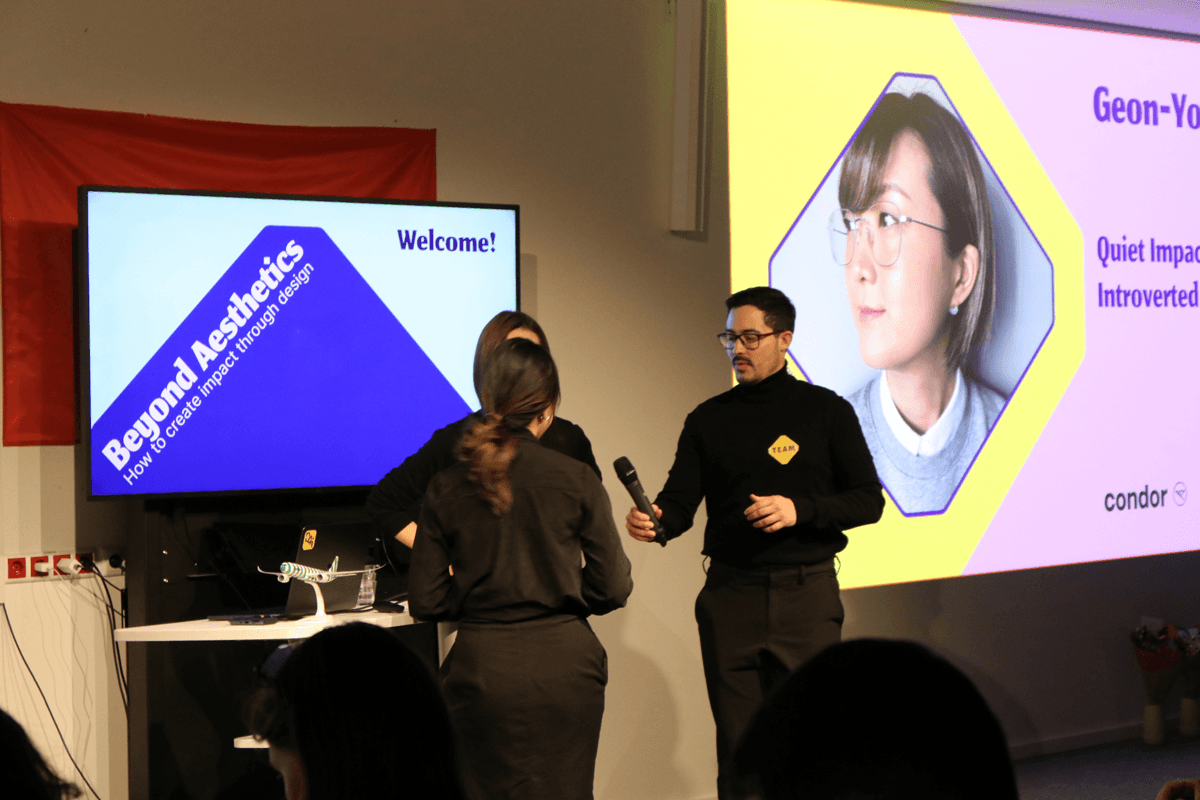 Two hosts on stage with the welcome slide