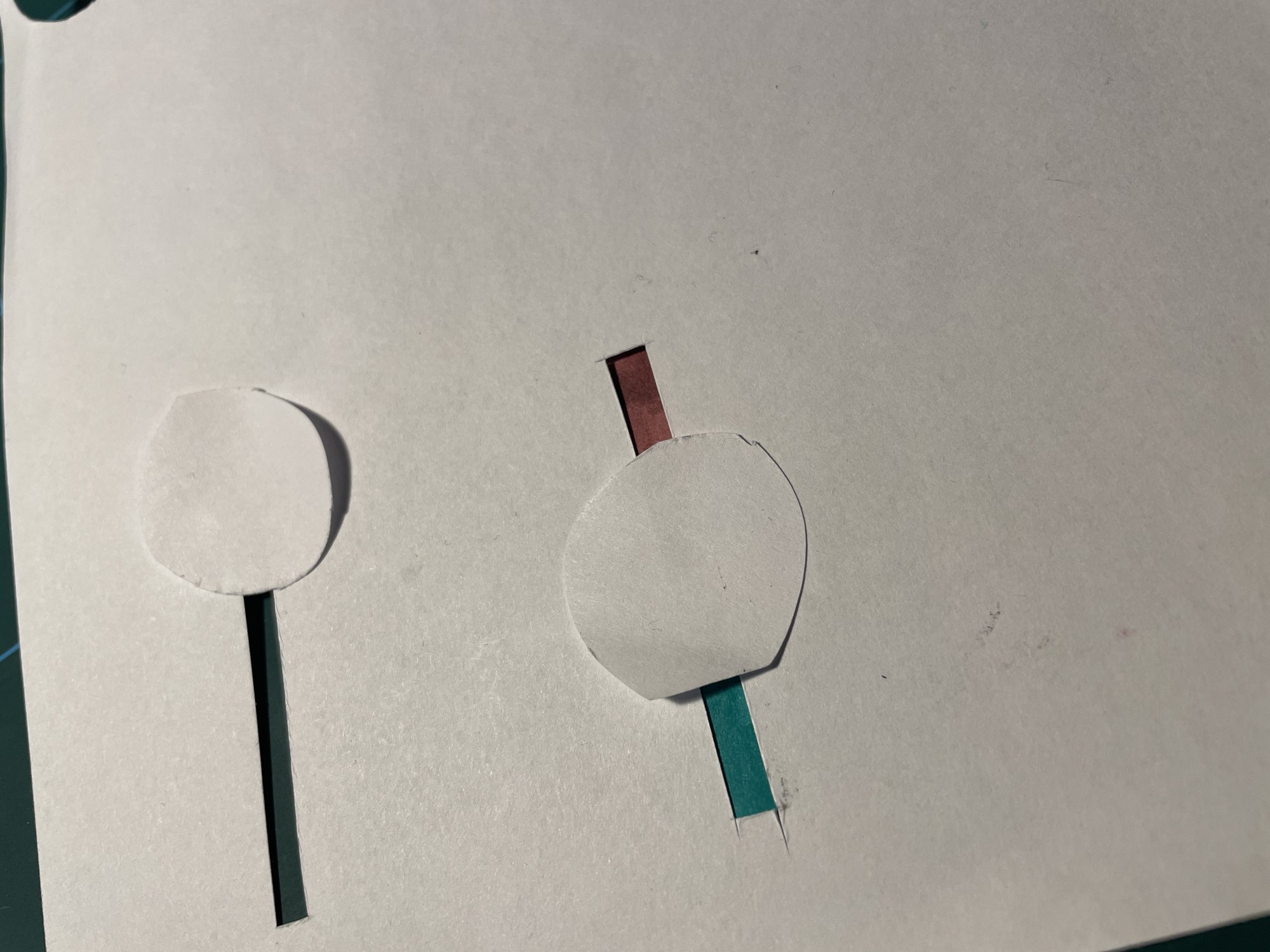 Paper prototype with paper circles on sliding strips cut into a page