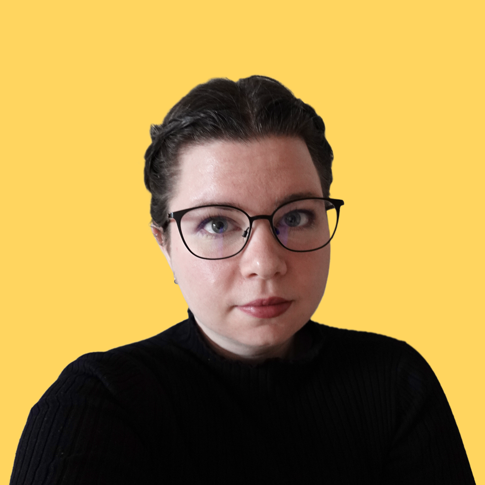 Portrait of Réka Kereki wearing glasses and a black top, on a yellow background